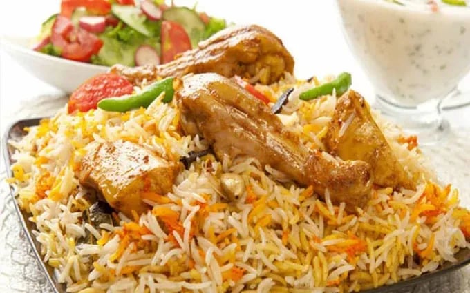 Delicious chicken biryani served with salad and raita, showcasing vibrant colors and aromatic spices.