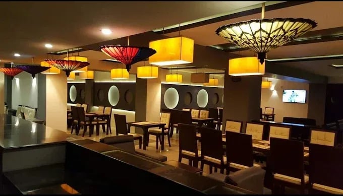 Elegant restaurant interior featuring wooden tables, stylish chairs, and decorative pendant lamps in warm colors.